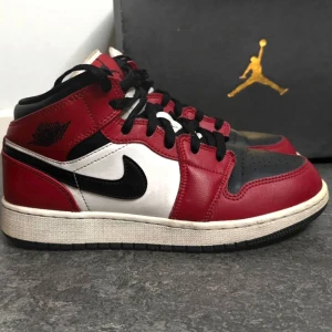 Nike Air Jordan 1 Mid Chicago - Säljer ett par klassiska Nike Air Jordan 1 Mid i Chicago. Skorna har svart, röd och vit läderöverdel, svart swoosh och svarta skosnören. Ikonisk Jordan logga på sidan och röd etikett på plösen. 