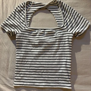 Randig ribbad topp med öppen rygg från Gina Tricot - Säljer en vit/svart randig ribbad topp från Gina Tricot. Storlek S, som ny! Kom med bud!🩷