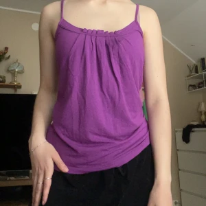Lila linnetopp från Story - Säljer en lila linnetopp från Story med smala axelband och lätt rynkade detaljer framtill. Perfekt för varma dagar och enkel att matcha med olika outfits.