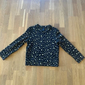 Leopardmönstrad tröja från Marc by Marc Jacobs - Säljer en snygg långärmad tröja från Marc by Marc Jacobs med leopardmönster i svart och guld. Tröjan har rund halsringning och är tillverkad i ett mjukt material som känns lyxigt. Perfekt för dig som vill sticka ut med en trendig look. Upplevs mer som XS. 