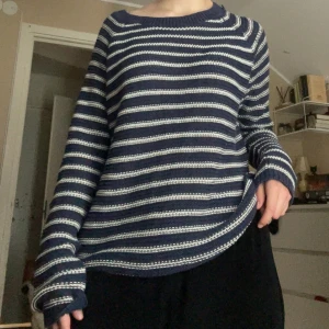 Randig stickad tröja från H&M - Säljer en blå stickad tröja med vita ränder från H&M i storlek M. Tröjan har rund halsringning och långa ärmar. Perfekt för kyligare dagar och enkel att matcha med jeans eller kjol. Små defekter i vänster armhåla samt kragen. Se bilder 4 & 5.