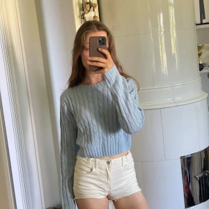 Ljusblå croppad stickad tröja från H&M Divided - Säljer en ljusblå croppad stickad tröja från H&M Divided. Tröjan har ett klassiskt kabelstickat mönster, rund halsringning och långa ärmar. Perfekt att styla med jeans eller kjol. Inte jättetjock och skönt material men har för mycket kläder..