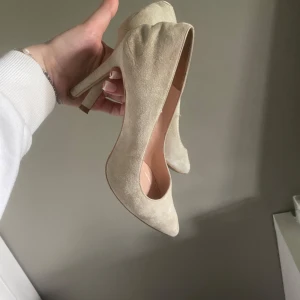 Beiga mocka klackskor - Snygga pumps i beige mocka med spetsig tå och hög klack. Skorna har en klassisk och stilren design som passar perfekt till dig som vill ha en clean och elegant look. Från zalando.