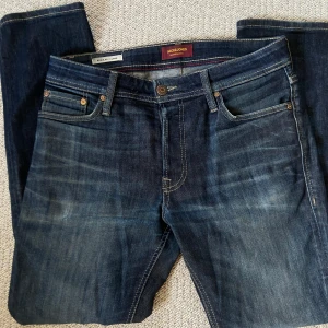Mörkblå jeans från Jack & Jones - Snygga mörkblå jeans från Jack & Jones. De har en regular passform och är perfekta för en avslappnad stil. Märkeslappen i läder på baksidan har en liten defekt men ingen som påverkar helheten. Skriv om du har funderingar! 🔥 W30 L30