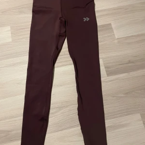 Lila/röda träningsleggings - Lila/röda träningleggings, perfekta för träning. De har en tight passform som ger bra stöd. Materialet är stretchigt och bekvämt, vilket gör dem idealiska för olika typer av aktiviteter.