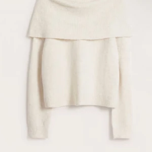 Vit stickad tröja med bred krage - Säljer en mysig vit stickad tröja med en bred krage som kan bäras offshoulder. Perfekt för höst eller våriga dagar med sin mjuka och bekväma passform. Tröjan har långa ärmar och ribbade kanter.
