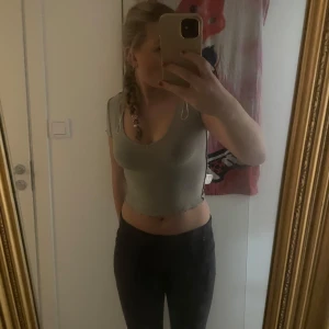 Grå croppad topp - Säljer en stilren grå croppad topp med korta ärmar. Perfekt för en avslappnad look. Toppen har en enkel design som gör den lätt att matcha med olika outfits.