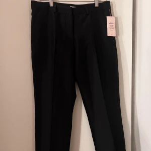 Svarta kostymbyxor från Nelly - Snygga svarta kostymbyxor från Nelly med låg midja och raka nedtill. Nya med prislapp 