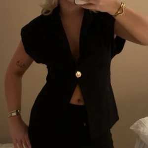 Fest topp från Zara - En svart festtopp från zara med gulddetaljer, som en kortärmad kavaj. Jag har dock klippt bort vadderingarna i axlarna men inget som syns utifrån. 