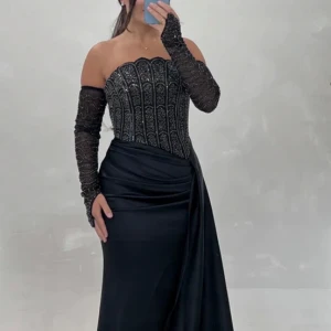 Svart klänning - Elegant svart klänning med glittriga paljettdetaljer på överdelen. Klänningen har en lång, svepande kjol och avtagbara ärmar. Perfekt för en glamorös kväll.