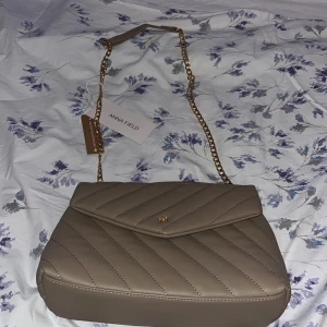 Beige axelväska från Anna Field - Snygg beige axelväska från Anna Field med quiltad design och guldfärgad kedja. Aldrig använd lappen kvar.