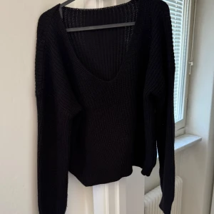 Svart stickad tröja med v-ringning - Säljer en stilren svart stickad tröja med djup v-ringning. Tröjan har långa ärmar och en bekväm passform, perfekt för kyligare dagar. Enkelt att matcha med olika outfits.