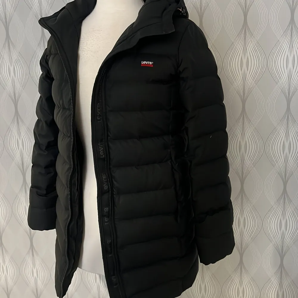 Säljer en stilren svart dunjacka från Levi's. Jackan har en dragkedja framtill och är långärmad med en quiltad design. Perfekt för kyliga dagar.. Takit.