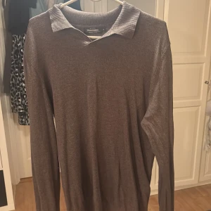 Brun tröja från Dressmann - Säljer en stilren brun tröja från Dressmann i bomull. Tröjan har en klassisk krage och långa ärmar, perfekt för en avslappnad men ändå uppklädd look.