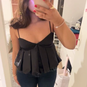 Svart satinlinne - Snygg svart satinlinne med smala axelband och v-ringning. Toppen har en lös passform med veckade detaljer som ger en elegant look. Perfekt för en kväll ute eller en speciell tillställning. Från H&M och i väldigt bra skick, perfekt festtopp. Storlek S!