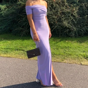 Ljuslila balklänning  - Elegant ljuslila långklänning med offshoulder-design och slits. Klänningen har en tight passform som framhäver figuren. Passar perfekt till bal, bröllop och fest. Storlek, 36/S stretchigt material. 