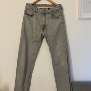 Grå jeansbyxor - Snygga grå jeansbyxor med en klassisk femficksdesign. Byxorna har en rak passform och är perfekta för en avslappnad stil. De har en dragkedja och knapp framtill.