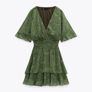 Grön mönstrad klänning från Zara - Säljen en otroligt snygg grön klänning från Zara med ett unikt mönster. Den har en v-ringad design och korta ärmar. Klänningen har en smickrande passform med volangdetaljer i kjolen. Köpt i England för någon sommarsen, inga defekter som ny! Pris kan diskuteras, lägger in egna bilder imorgon💞❤️