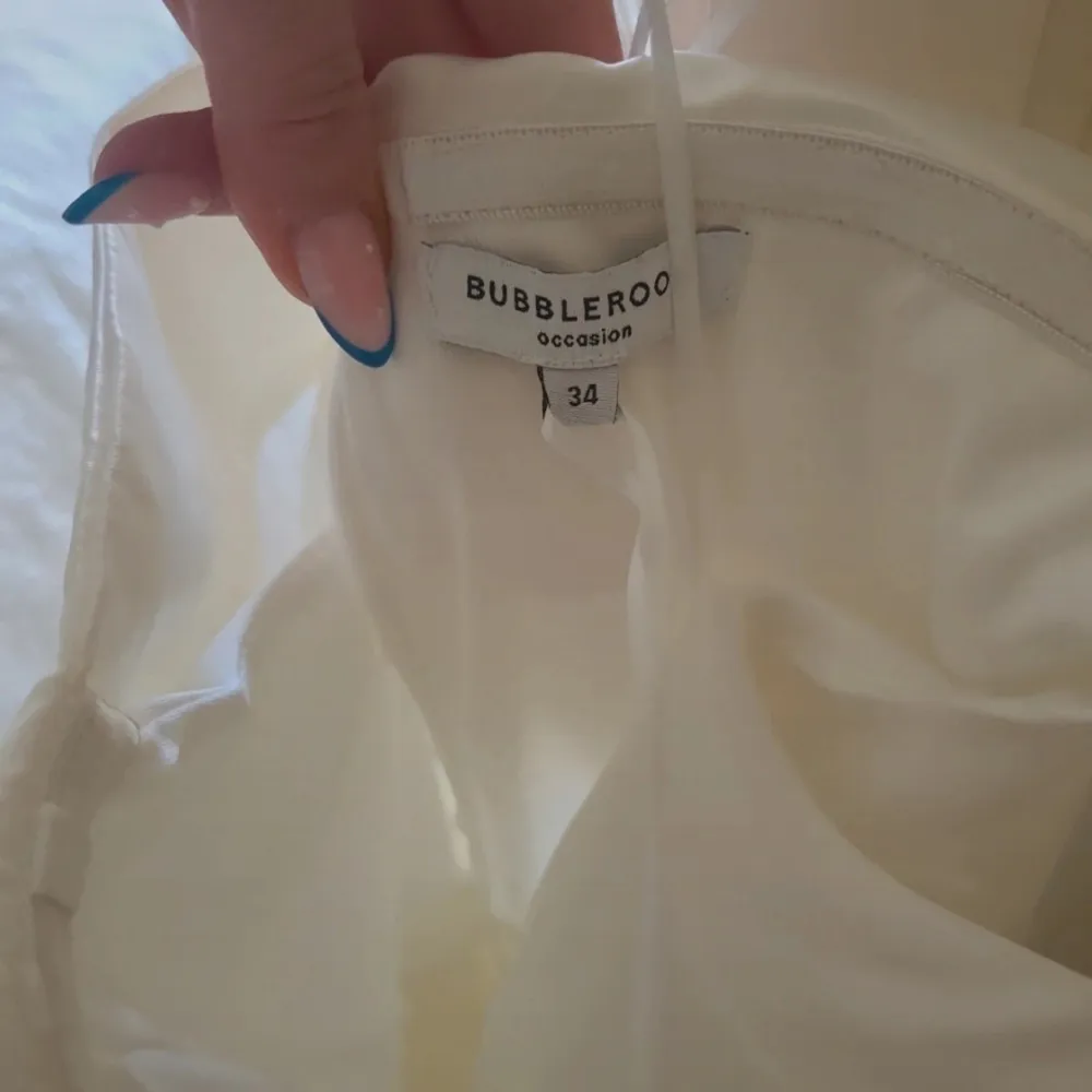 Säljer en elegant vit off shoulder klänning från Bubbleroom. Klänningen har en vacker, veckad kjol och är perfekt för speciella tillfällen. Den är i storlek 34 och ger en stilren och sofistikerad look.. Mekot.