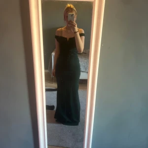 Mörkgrön långklänning från WalG - Säljer en jätte fin mörkgrön bal/långklänning från WalG med offshoulder-design. Klänningen har en figurnära passform och är perfekt för bal! Använd en gång och är i jättebra skick! 