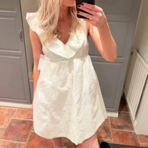 Studentklänning - Vit klänning med volangdetaljer från Bubbleroom. Perfekt till studenten. Aldrig använd 