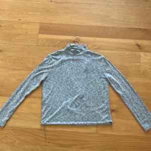 Grå omlottopp från NLY Trend - Det är ryggen som gör tröjan, öppning i ryggen, hänger så fint! Säljer en stilren grå omlottopp från NLY Trend i storlek M. Toppen har en omlottdesign med långa ärmar och en mjuk, bekväm passform. 