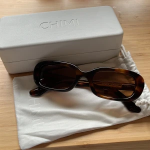 Bruna solglasögon från Chimi - Snygga bruna solglasögon från Chimi i modellen '12 Tortoise'. De har en rektangulär form och kommer med ett stilrent fodral och en vit påse. Perfekta för en solig dag! Aldrig använd, perfekt skick💗