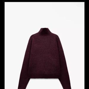 Vinröd stickad polotröja - Säljer en mysig vinröd stickad polotröja med hög krage. Perfekt för kyliga dagar i skidbacken eller en avslappnad dag hemma. Tröjan har långa ärmar och en enkel design som gör den lätt att matcha med olika outfits. Helt oanvänd  prislappen är kvar 