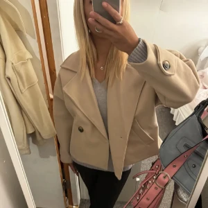 Beige kappa med knappar - Säljer en stilren beige kappa med stora knappar och bred krage. Jackan har en kortare passform och är perfekt för höst och vår. Den har långa ärmar och en klassisk look som passar till många olika outfits.❤️❤️❤️