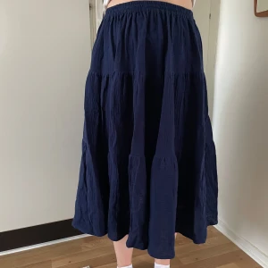 Mörkblå kjol - Säljer en mörkblå kjol med elastisk midja. Kjolen har en luftig och bekväm passform, perfekt för både vardag och speciella tillfällen. Materialet (double gauze) ger ett fint fall och kjolen är lätt att matcha med olika toppar. - egensydd, aldrig använd.  @sytanten_ (Instagram)