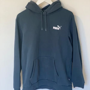 hoodie från Puma (mörkgrön) - Säljer en hoodie från Puma med klassisk logga på bröstet. Tröjan har en bekväm passform med känguruficka och justerbar huva med dragsko. Sista bilden visar den lilla skadan på tröjan.