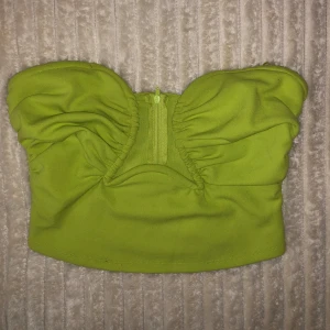 Grön axelbandslös topp - Snygg grön axelbandslös topp. Använd en gång. Perfekt för en somrig look eller en utekväll. Toppen har en smickrande passform med rynkade detaljer framtill.
