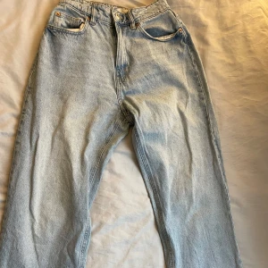 Ljusblå jeans från H&M - Säljer ett par baggy ljusblå jeans från H&M. De har en klassisk femficksdesign och knappgylf. Perfekta för en avslappnad stil.