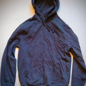 Mörkblå hoodie - Säljer en stilren mörkblå hoodie med justerbar huva och praktisk magficka. Perfekt för en avslappnad look.