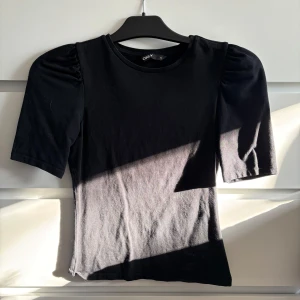 Svart topp från ONLY - Säljer en stilren svart topp från ONLY i storlek XS. Toppen har korta ärmar med en lätt puffig design och en rund halsringning. Hör av dig vid intresse 🤗