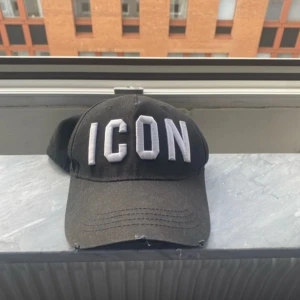 Svart keps från Dsquared2 - Snygg svart keps från Dsquared2 med texten 'ICON' broderad framtill och märkesnamnet baktill. Perfekt för en cool och avslappnad stil.