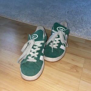 Gröna Adidas sneakers - Snygga gröna Adidas sneakers med vita detaljer och snörning. Perfekta för en avslappnad stil. De har en klassisk design med märkets ikoniska ränder på sidan. Pris kan diskuteras vid snabb affär