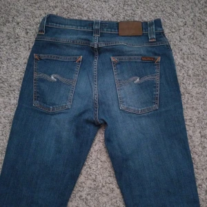 Nudie jeans grim tim - Säljer ett par snygga Nudie grim tim. Jeansen är i mycket fint skick utan defekter på utsidan men säljer då de är för små. Jeansen sitter slim och har storlek w29 l34 men passar även w28 l32. Hål i ena fickan men som lagats! 