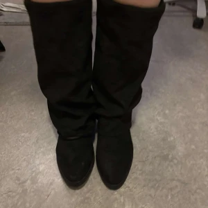 Svarta stövlar i mocka - Snygga svarta stövlar i mocka med en klassisk design. De har en spetsig tå och är perfekta för både vardag och speciella tillfällen. Stövlarna har en stilren look och är lätta att matcha med olika outfits. Är storlek 40 men passar mer 39. Klacken är ca 4,5 cm