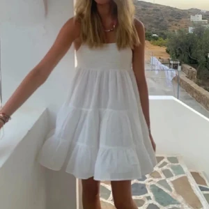 Vit ärmlös klänning - Lånade bilder. Söt vit klänning med smala axelband och volangdetaljer. Perfekt för varma sommardagar. Säljer då det inte kommer till användning, använt 1 gång. Priset kan diskuteras.