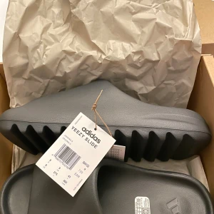 Adidas Yeezy Slide i färgen Granite - Yeezy slides i granite färg, helt nya deadstock. Kvitto finns digitalt bara att fråga. Ingen prissänkning