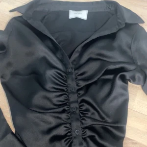 Svart blus från Neo Noir - Elegant svart blus från Neo Noir med knappar framtill och långa ärmar. Endast använd en gång. Skriv om fler bilder