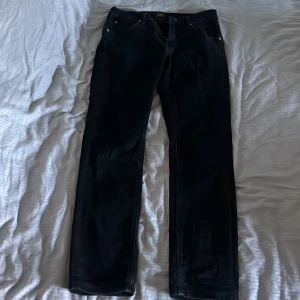 Svarta jeans från Lee - Snygga svarta jeans från Lee med klassisk femficksdesign och knappgylf. Perfekta för en stilren look. De har en rak passform och är tillverkade i slitstarkt denim.