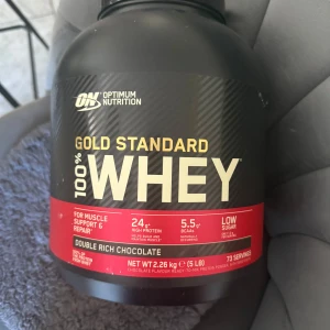 Optimum Nutrition Gold Standard 100% Whey - Säljer en stor burk med Optimum Nutrition Gold Standard 100% Whey i smaken Double Rich Chocolate. Innehåller 2,26 kg (5 lb) och ger 73 portioner. Perfekt för muskelstöd och återhämtning med 24 g protein per portion och låg sockerhalt.