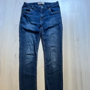 Blå jeans från Levi's - Snygga blå jeans från Levi's med klassisk femficksdesign och knappgylf. Perfekta för en avslappnad stil. De har en bekväm passform och är tillverkade i slitstarkt denim.