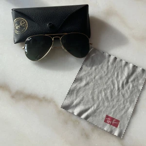 Ray-Ban solglasögon - Snygga Ray-Ban solglasögon med guldfärgad metallram och mörka glas. Perfekt för en stilren look. Kommer med originalfodral och putsduk original pris 1900 kr säljs för 800 kr aldrig använt