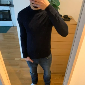 Mörkblå stickad tröja - Säljer en stilren mörkblå tröja med långa ärmar, perfekt för sommaren. Tröjan har en enkel design och är lätt att matcha med olika outfits. Nypris:699Kr