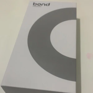 Bond Touch armband - Säljer ett Bond Touch armband i svart med en stilren design. Armbandet har en justerbar rem och en oval enhet som gör det enkelt att hålla kontakten med nära och kära. Perfekt för att skicka beröringar över avstånd.