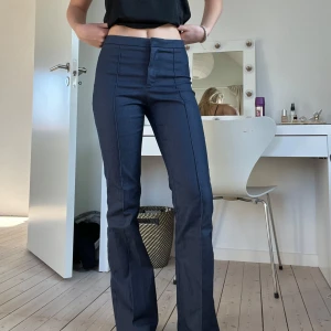 Mörkblå bootcut - Snygga mörkblå byxor med bootcut-stil och medelhög midja. Perfekta för en stilren look. Byxorna har en slät design utan synliga detaljer och är tillverkade i ett bekvämt material.