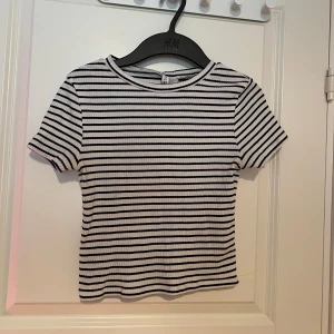 Randig ribbad topp från H&M - Säljer en stilren randig ribbad topp från H&M. Den är kortärmad och croppad med svarta och vita ränder. 